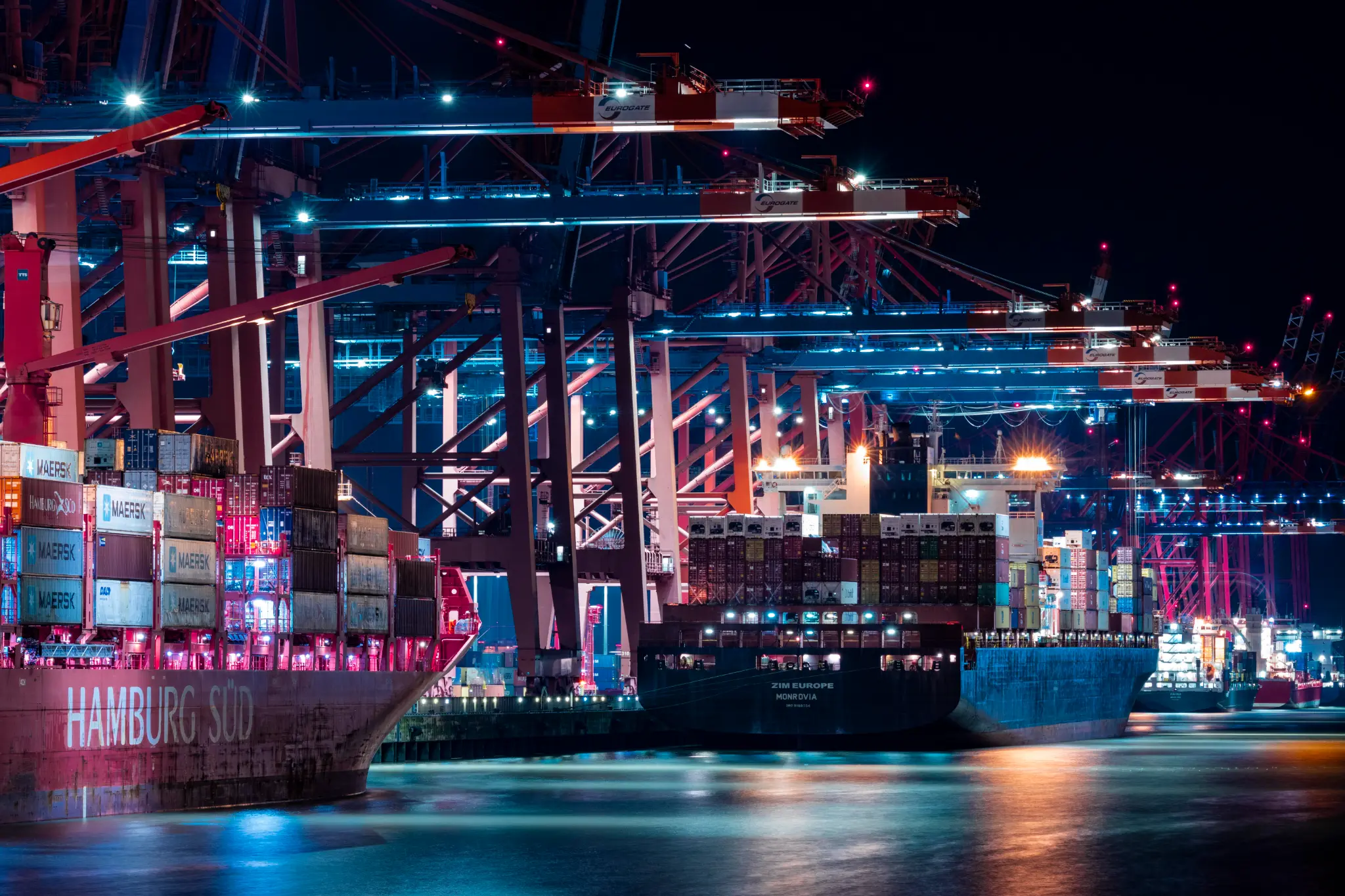 Container cranes and cargo ships operating at a port at night